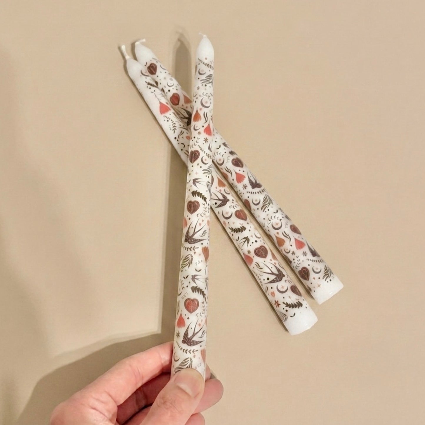 Three patterned candles held against a beige background