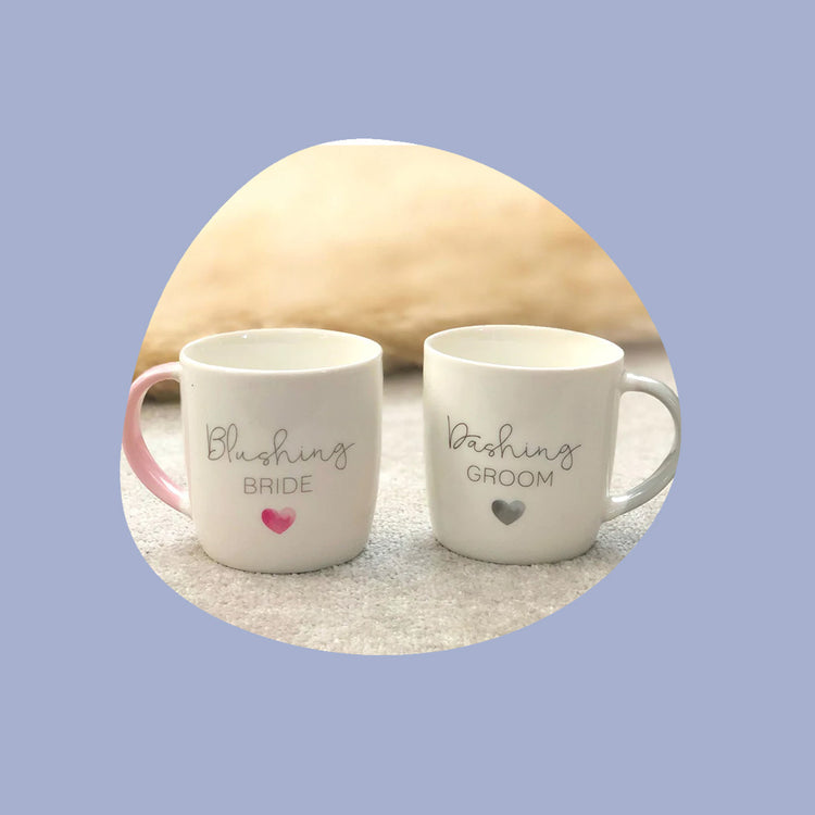 A wedding gift mug with text "Blushing pride and Dashing Groom" written on the mugs.