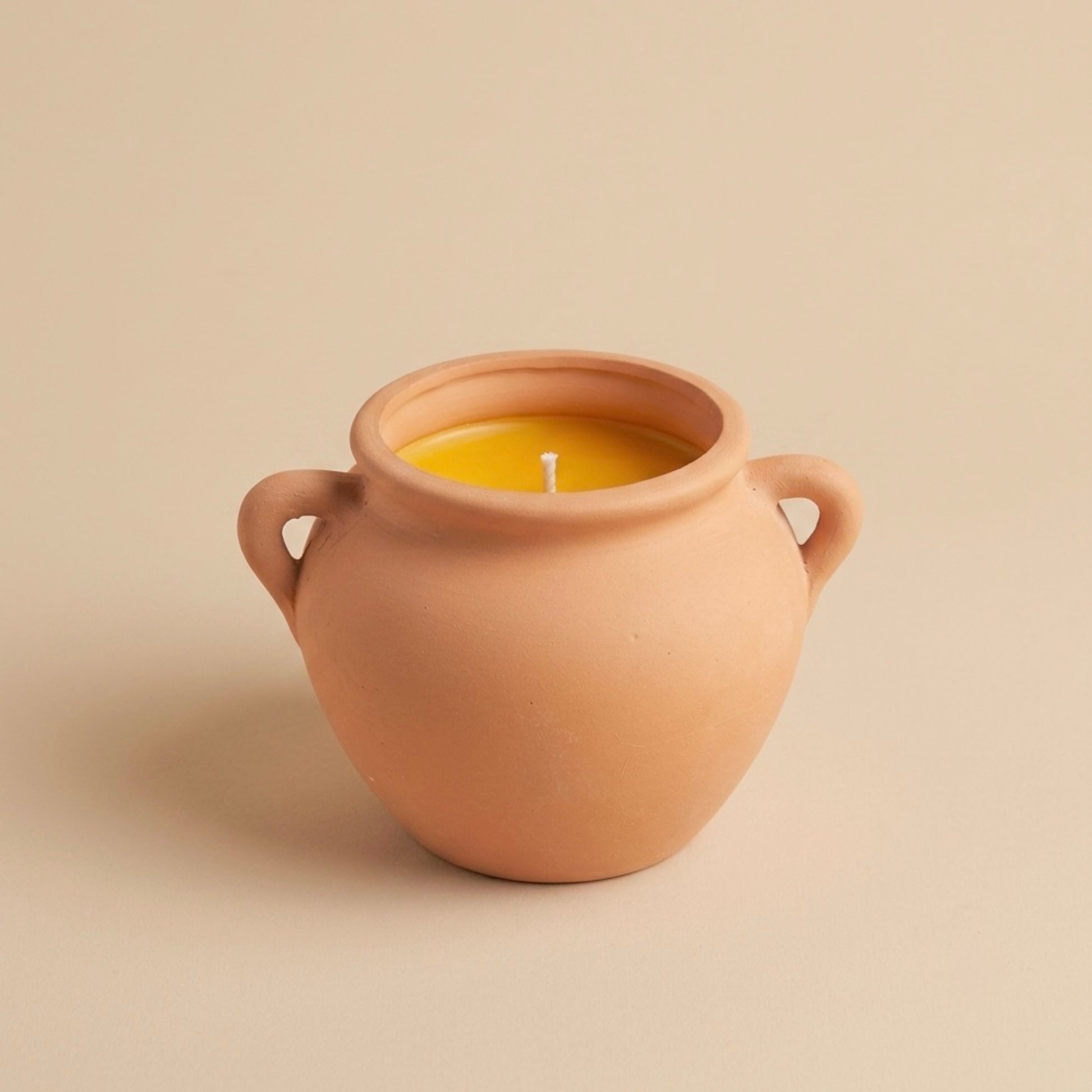 Ceramic pot with a candle inside on a beige background