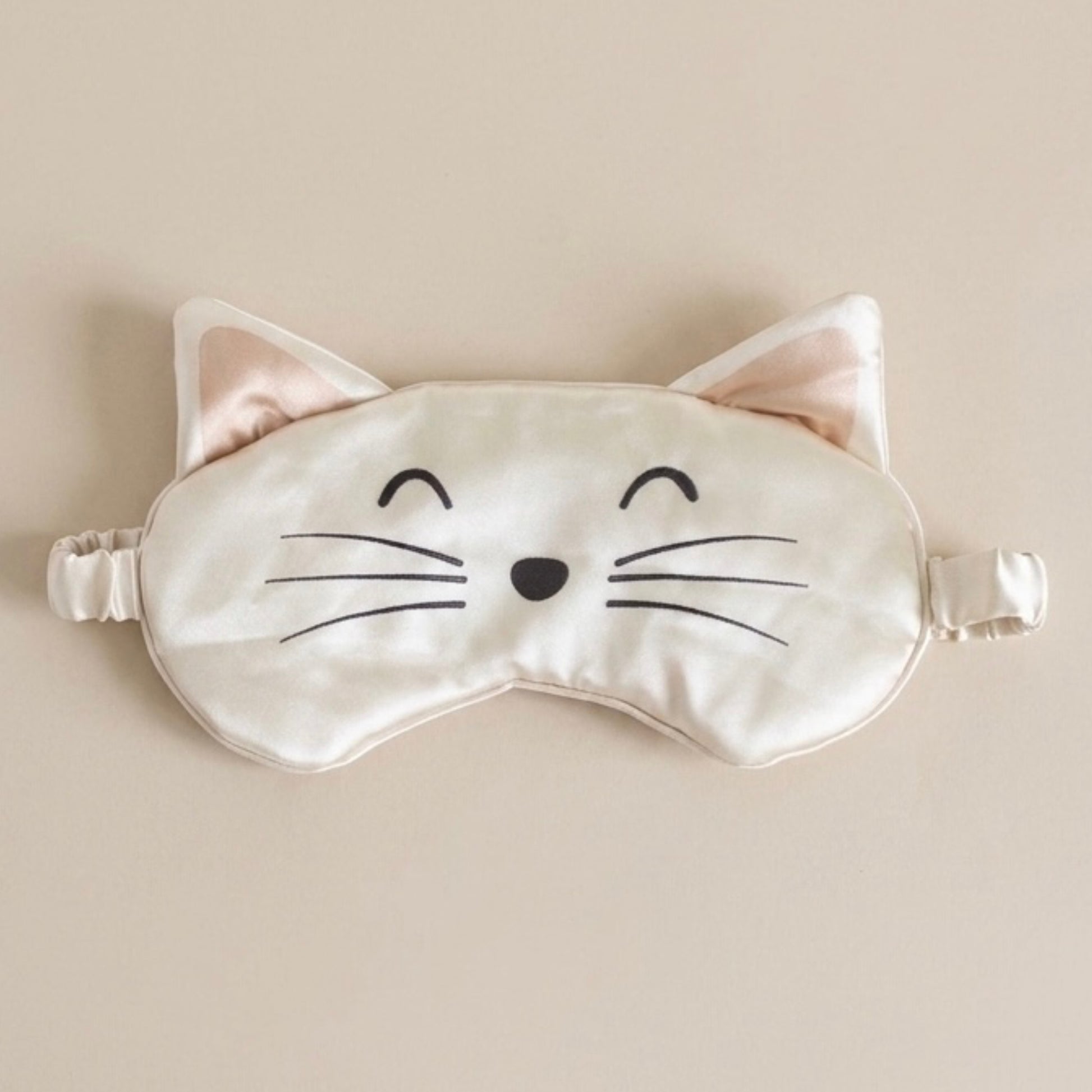 Cat-shaped sleep mask on a beige background