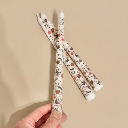 Three patterned candles held against a beige background